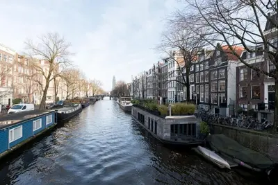 a river with boats in a city with buildings at The Prinsen in Amsterdam