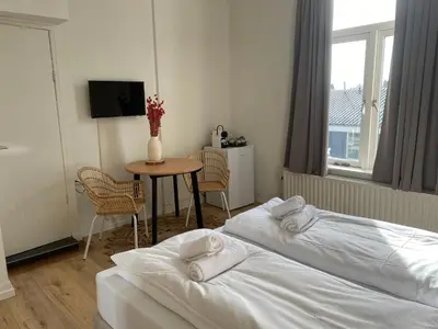 a room with two beds and a table with a tv at Hotel Doppenberg in Zandvoort