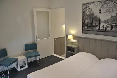a hotel room with a bed and two chairs at Hotel Doppenberg in Zandvoort