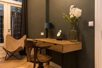 a desk with a vase of flowers on a wall at B&B Felix in Amsterdam