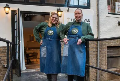 two women in aprons are standing on a railing at Hofje van Sint Jan in Gouda