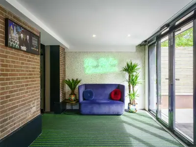 a blue chair in a room with a neon sign at ibis Styles Amsterdam Amstel in Amsterdam