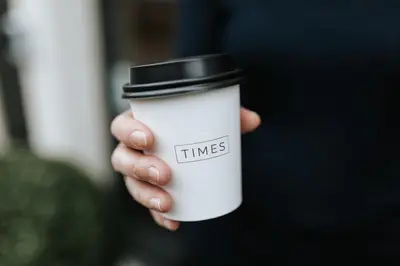 a hand holding a white coffee cup with a black top at The Times Hotel in Amsterdam