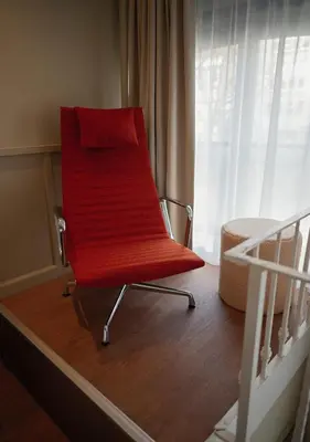 a red chair sitting in a room next to a bed at The Times Hotel in Amsterdam
