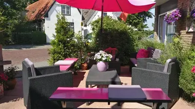 a patio with chairs and a table with a pink umbrella at Hotel De Weyman in Santpoort-Noord