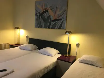 two beds in a hotel room with two lamps at Hotel De Weyman in Santpoort-Noord