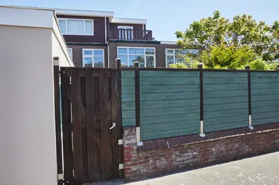 a fence with a wooden gate in front of a house at Het Krekeltje in Zandvoort