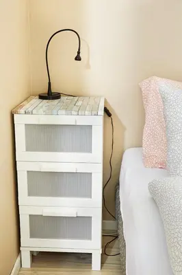 a white dresser with a lamp on it next to a bed at Het Krekeltje in Zandvoort