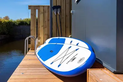 a blue and white boat sitting on a dock at Cabana incl boat, jacuzzi,subboarts on a quiet park with private parking in Loosdrecht