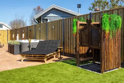 a wooden fence with a bench in a yard at Cabana incl boat, jacuzzi,subboarts on a quiet park with private parking in Loosdrecht