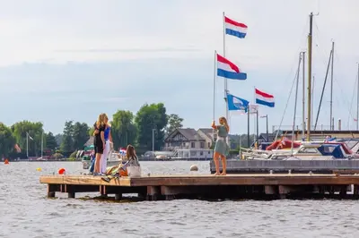 a group of people standing on a dock with flags at Cabana incl boat, jacuzzi,subboarts on a quiet park with private parking in Loosdrecht