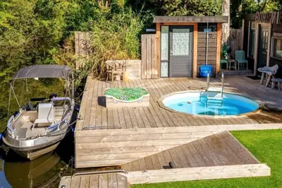 a deck with a pool and a boat on the water at Bohemian included boat supboards and pool 5 minutes by boat from parking to the bohemien in Loosdrecht