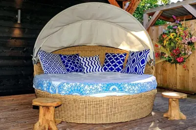 a wicker chair sitting on a patio with two stools at Bohemian included boat supboards and pool 5 minutes by boat from parking to the bohemien in Loosdrecht