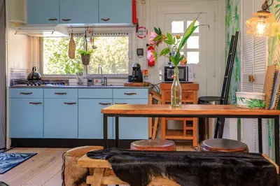 a kitchen with blue cabinets and a table with stools at Bohemian included boat supboards and pool 5 minutes by boat from parking to the bohemien in Loosdrecht