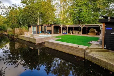 a house on the water next to a body of water at Bohemian included boat supboards and pool 5 minutes by boat from parking to the bohemien in Loosdrecht