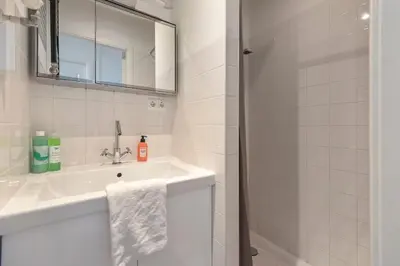a white bathroom with a sink and a mirror at 't Schelpje with free parking in Zandvoort