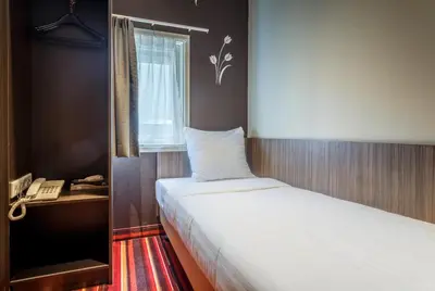 a bedroom with a bed and a phone next to a window at Mozart Hotel in Amsterdam