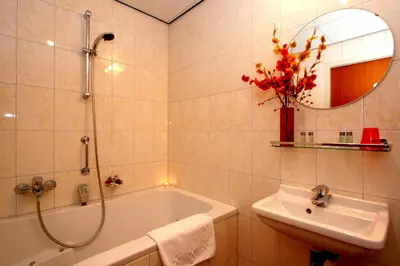 a bathroom with a tub and a sink and a mirror at Mozart Hotel in Amsterdam