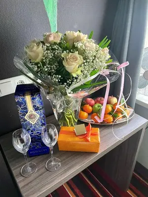 a table with a vase with roses and fruit and wine glasses at Mozart Hotel in Amsterdam