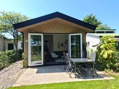 a conservatory with a table and chairs on a patio at Bungalowpark Mooyeveld in Egmond-Binnen