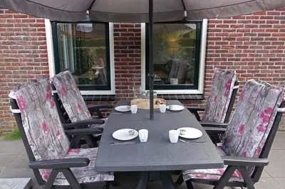 a table with chairs and an umbrella on a patio at Bungalowpark Mooyeveld in Egmond-Binnen