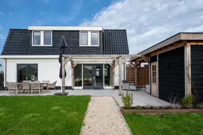 a house with a black roof and a patio at 8 persons waterfront Villa Tulpenacker in Roelofarendsveen