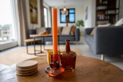 a candle and a bottle on a table in a living room at 8 persons waterfront Villa Tulpenacker in Roelofarendsveen