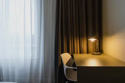 a desk with a lamp and a chair next to a window at Hotel Roemer Amsterdam in Amsterdam