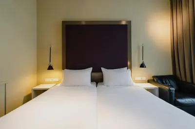 a large bed with two white pillows and a chair at Hotel Roemer Amsterdam in Amsterdam