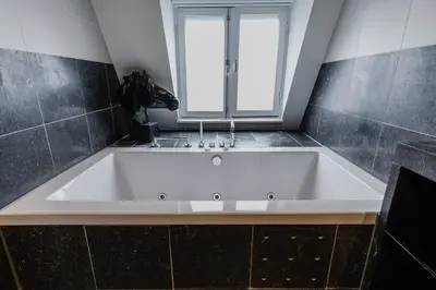 a large bath tub in a bathroom with a window at Hotel Roemer Amsterdam in Amsterdam