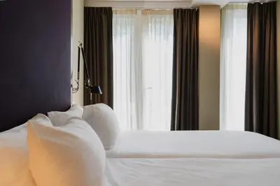 a bedroom with a bed with white pillows and a window at Hotel Roemer Amsterdam in Amsterdam
