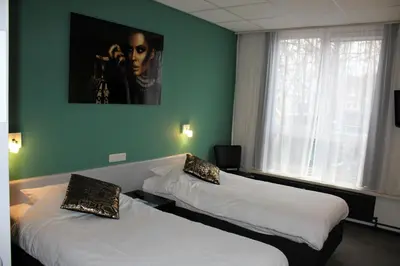 two beds in a room with green walls at Hotel Restaurant de Jonge Heertjes in Aalsmeer