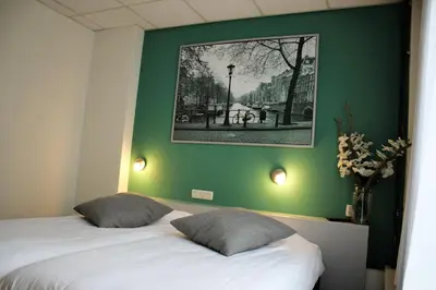 a bedroom with a green wall and a bed with two pillows at Hotel Restaurant de Jonge Heertjes in Aalsmeer