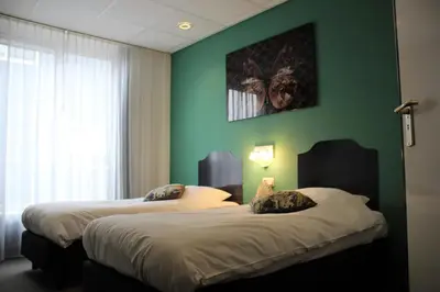 two beds in a room with a green wall at Hotel Restaurant de Jonge Heertjes in Aalsmeer
