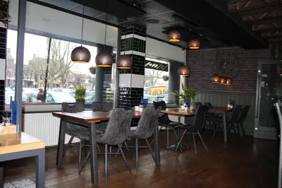 a restaurant with wooden tables and chairs and windows at Hotel Restaurant de Jonge Heertjes in Aalsmeer