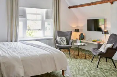 a bedroom with a bed and two chairs and a desk at Hotel Station Amstelveen in Amstelveen