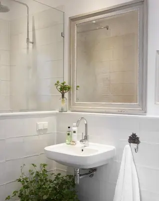 a white bathroom with a sink and a mirror at Hotel Station Amstelveen in Amstelveen