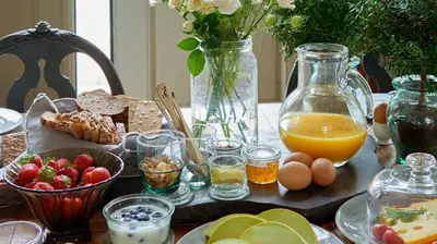 a table with a breakfast of eggs bread and orange juice at Hotel Station Amstelveen in Amstelveen