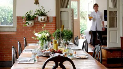 a table in a restaurant with a woman in the background at Hotel Station Amstelveen in Amstelveen