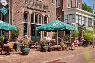 a group of people sitting at tables in front of a building at Hotel Station Amstelveen in Amstelveen
