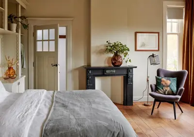 a bedroom with a bed and a chair and a fireplace at Hotel Station Amstelveen in Amstelveen