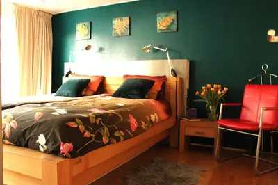 a bedroom with a bed and a red chair at Houseboat Orpheus in Amsterdam