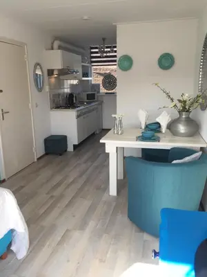 a kitchen with a white table and a blue chair at Huize de Weijde Blick in Wijk aan Zee
