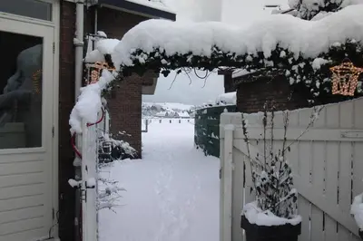 a snow covered entrance to a house with a fence at Huize de Weijde Blick in Wijk aan Zee