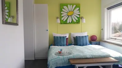 a bedroom with a bed with a flower picture on the wall at Huize de Weijde Blick in Wijk aan Zee