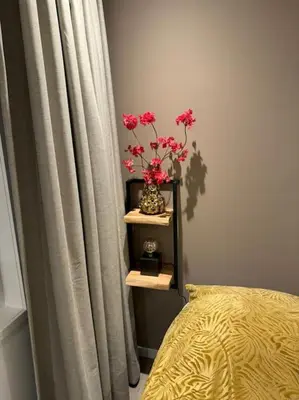 a vase with pink flowers on a shelf next to a curtain at Luxe woning Bubbles! Met airco en Parkeren op eigen grond in Castricum