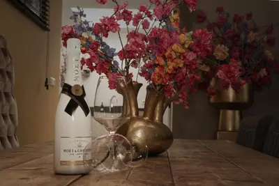 a table with a vase with flowers and a bottle of wine at Luxe woning Bubbles! Met airco en Parkeren op eigen grond in Castricum