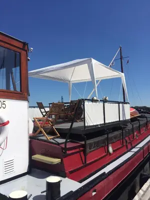 a red boat with a white canopy and chairs on it at Klipper Johanna in Monnickendam