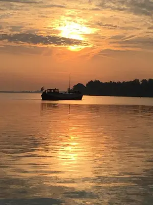 a boat sitting on the water at sunset at Klipper Johanna in Monnickendam