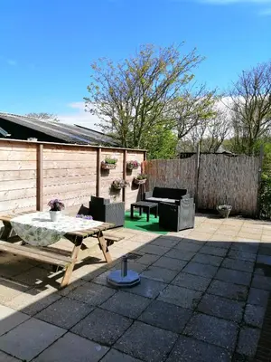 a patio with a table and chairs and a fence at Knusse vakantiewoning in Camperduin in Schoorl